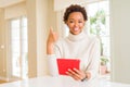 Young african american woman using tablet happy with big smile doing ok sign, thumb up with fingers, excellent sign