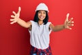 Young african american woman wearing architect hardhat looking at the camera smiling with open arms for hug Royalty Free Stock Photo