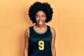 Young african american woman wearing basketball uniform sticking tongue out happy with funny expression Royalty Free Stock Photo
