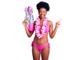 Young african american woman wearing bikini and hawaiian lei holding water gun smiling happy pointing with hand and finger to the Royalty Free Stock Photo