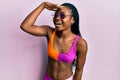 Young african american woman wearing bikini and sunglasses very happy and smiling looking far away with hand over head Royalty Free Stock Photo