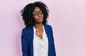 Young african american woman wearing business clothes and glasses in shock face, looking skeptical and sarcastic, surprised with Royalty Free Stock Photo