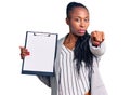 Young african american woman wearing business clothes holding clipboard pointing with finger to the camera and to you, confident Royalty Free Stock Photo