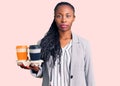 Young african american woman wearing business clothes holding take away cup of coffee thinking attitude and sober expression