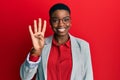 Young african american woman wearing business jacket and glasses showing and pointing up with fingers number four while smiling Royalty Free Stock Photo