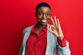 Young african american woman wearing business jacket and glasses smiling positive doing ok sign with hand and fingers Royalty Free Stock Photo