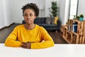 Young african american woman wearing casual clothes sitting on the table at home relaxed with serious expression on face Royalty Free Stock Photo