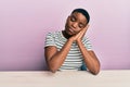 Young african american woman wearing casual clothes sitting on the table sleeping tired dreaming and posing with hands together Royalty Free Stock Photo