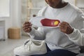 Young african woman holding sneakers insole in her hands at home.