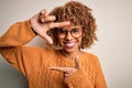 Young african american woman wearing casual sweater and glasses over white background smiling making frame with hands and fingers Royalty Free Stock Photo
