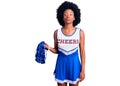 Young african american woman wearing cheerleader uniform holding pompom looking at the camera blowing a kiss on air being lovely