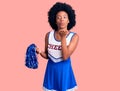 Young african american woman wearing cheerleader uniform holding pompom looking at the camera blowing a kiss with hand on air