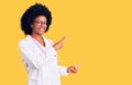 Young african american woman wearing doctor coat and stethoscope smiling and looking at the camera pointing with two hands and Royalty Free Stock Photo