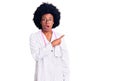 Young african american woman wearing doctor coat and stethoscope surprised pointing with finger to the side, open mouth amazed Royalty Free Stock Photo