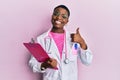 Young african american woman wearing doctor stethoscope holding clipboard smiling happy and positive, thumb up doing excellent and Royalty Free Stock Photo