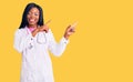 Young african american woman wearing doctor stethoscope smiling and looking at the camera pointing with two hands and fingers to Royalty Free Stock Photo