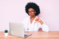 Young african american woman wearing doctor stethoscope working using computer laptop with angry face, negative sign showing Royalty Free Stock Photo