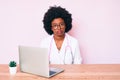 Young african american woman wearing doctor stethoscope working using computer laptop with serious expression on face Royalty Free Stock Photo