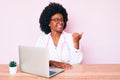 Young african american woman wearing doctor stethoscope working using computer laptop smiling with happy face looking and pointing Royalty Free Stock Photo