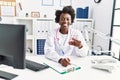 Young african american woman wearing doctor uniform holding pills at clinic Royalty Free Stock Photo