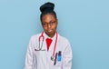 Young african american woman wearing doctor uniform and stethoscope looking sleepy and tired, exhausted for fatigue and hangover, Royalty Free Stock Photo