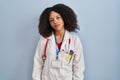 Young african american woman wearing doctor uniform and stethoscope looking sleepy and tired, exhausted for fatigue and hangover, Royalty Free Stock Photo