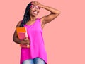 Young african american woman wearing glasses holding book stressed and frustrated with hand on head, surprised and angry face Royalty Free Stock Photo