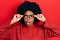 Young african american woman wearing glasses in shock face, looking skeptical and sarcastic, surprised with open mouth Royalty Free Stock Photo