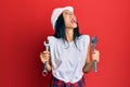 Young african american woman wearing hardhat holding wrench angry and mad screaming frustrated and furious, shouting with anger Royalty Free Stock Photo