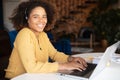 Young African-American woman wearing headset using laptop for remote work