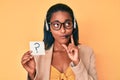 Young african american woman wearing operator headset holding question mark serious face thinking about question with hand on Royalty Free Stock Photo