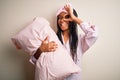 Young african american woman wearing pajama and eye mask hugging bed pillow with happy face smiling doing ok sign with hand on eye Royalty Free Stock Photo