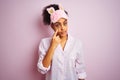 Young african american woman wearing pajama and mask over isolated pink background Pointing to the eye watching you gesture, Royalty Free Stock Photo