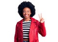 Young african american woman wearing red leather jacket smiling with happy face winking at the camera doing victory sign Royalty Free Stock Photo