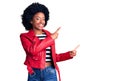Young african american woman wearing red leather jacket smiling and looking at the camera pointing with two hands and fingers to Royalty Free Stock Photo