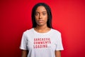 Young african american woman wearing sarcasm coments text on t-shirt over red background with a confident expression on smart face