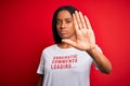 Young african american woman wearing sarcasm coments text on t-shirt over red background with open hand doing stop sign with