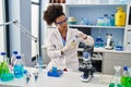 Young african american woman wearing scientist uniform closing bottle at laboratory