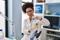 Young african american woman wearing scientist uniform closing bottle at laboratory