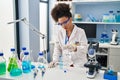 Young african american woman wearing scientist uniform using pipette working at laboratory Royalty Free Stock Photo