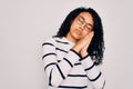 Young african american woman wearing striped sweater and glasses over white background sleeping tired dreaming and posing with Royalty Free Stock Photo