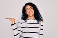 Young african american woman wearing striped sweater and glasses over white background smiling cheerful presenting and pointing Royalty Free Stock Photo