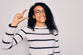 Young african american woman wearing striped sweater and glasses over white background smiling and confident gesturing with hand Royalty Free Stock Photo