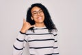 Young african american woman wearing striped sweater and glasses over white background smiling doing phone gesture with hand and Royalty Free Stock Photo