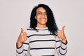 Young african american woman wearing striped sweater and glasses over white background success sign doing positive gesture with Royalty Free Stock Photo