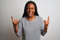 Young african american woman wearing striped t-shirt standing over isolated white background shouting with crazy expression doing Royalty Free Stock Photo