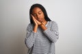 Young african american woman wearing striped t-shirt standing over isolated white background sleeping tired dreaming and posing Royalty Free Stock Photo