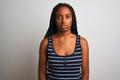 Young african american woman wearing striped t-shirt standing over  white background with serious expression on face Royalty Free Stock Photo