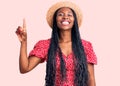 Young african american woman wearing summer hat showing and pointing up with finger number one while smiling confident and happy Royalty Free Stock Photo