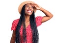 Young african american woman wearing summer hat very happy and smiling looking far away with hand over head Royalty Free Stock Photo